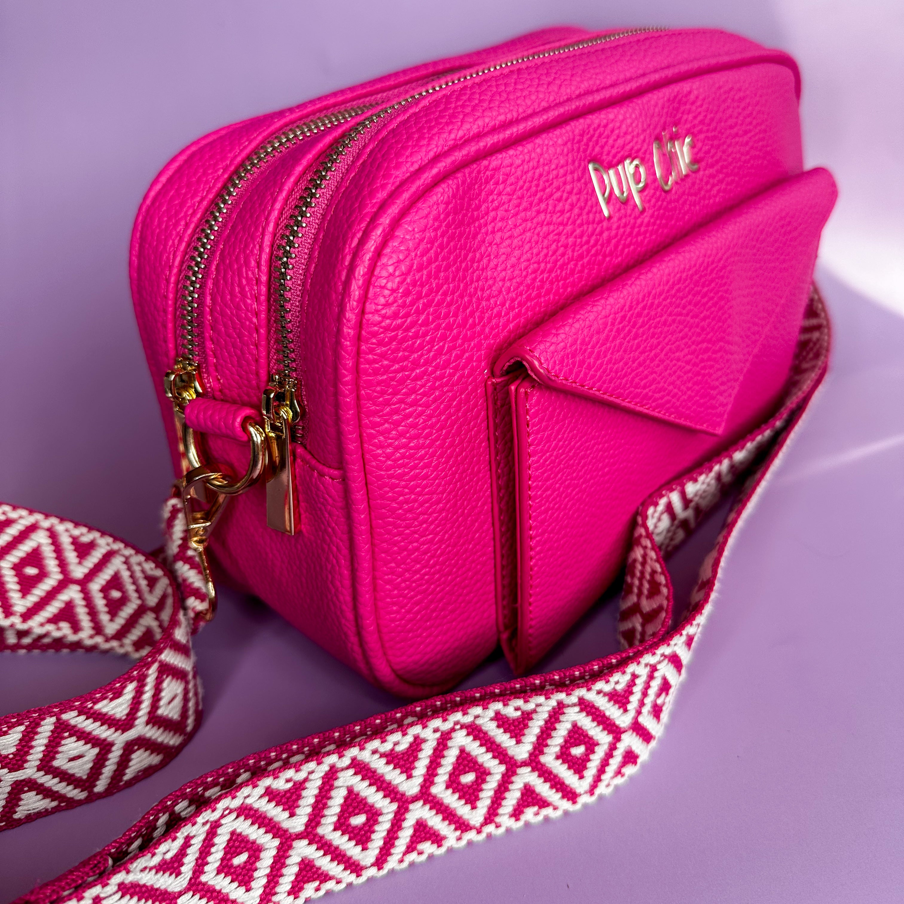 Pink handbag with a patterned strap on a purple background